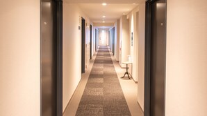 A hotel hallway with doors numbered 710 and 701, a carpeted floor, and a small table with a lamp. - Hotel Livemax Hakata-ekimae (Fukuoka)