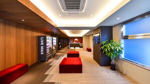 A hotel lobby with a wooden floor, red seating, a reception desk, and a large window. - Hotel Livemax Hakata-ekimae (Fukuoka)
