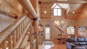 A spacious living area with a wooden staircase, a leather sofa, and a dining area with a table and chairs. - Arrow Lodge (Lead)