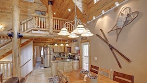A spacious wooden interior with a dining area, kitchen, and a staircase leading to an upper level. - Arrow Lodge (Lead)