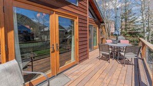 A wooden deck with outdoor furniture, a sliding glass door, and a view of a residential area. - 2BR 2BA In Town, Pet Friendly, Fenced Yard, Walkable, Large Deck (Crested Butte)