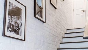 A staircase with white brick walls and framed pictures. - Renovated 2story(7C) OSU/ExpoCenter/Central ❤NearEVERYTHING (Columbus)