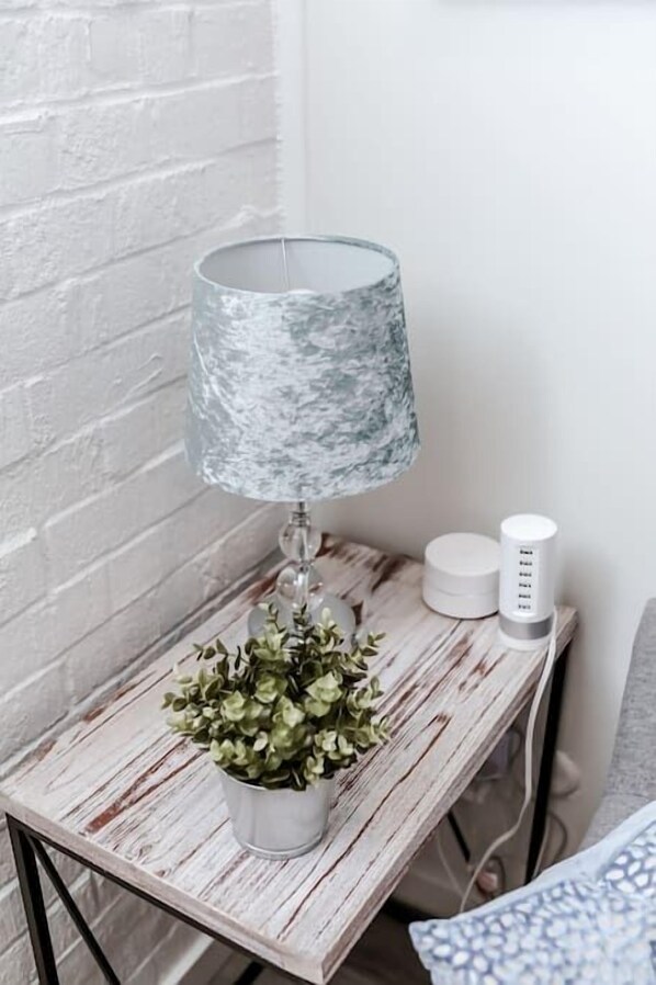 A lamp with a textured shade, a small potted plant, and a white cylindrical object on a wooden table. - Renovated 2story(7C) OSU/ExpoCenter/Central ❤NearEVERYTHING (Columbus)