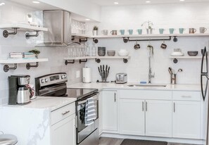 A modern kitchen with white cabinets, stainless steel appliances, and a variety of kitchenware on shelves. - Renovated 2story(7C) OSU/ExpoCenter/Central ❤NearEVERYTHING (Columbus)