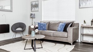 A modern living room with a grey sofa, a round coffee table, and a black chair. - Newly Renovated (9E) OSU/ExpoCenter/Central ❤NearEVERYTHING (Columbus)