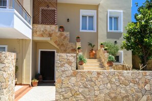 A multi-story building with stone walls, a staircase with potted plants, and a balcony with a lattice railing. - Stunning Comfortable Family House in Chania (Chania)