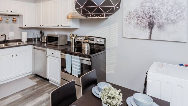 A modern kitchen with white cabinets, a built-in oven, and a dining area with a table set for two.