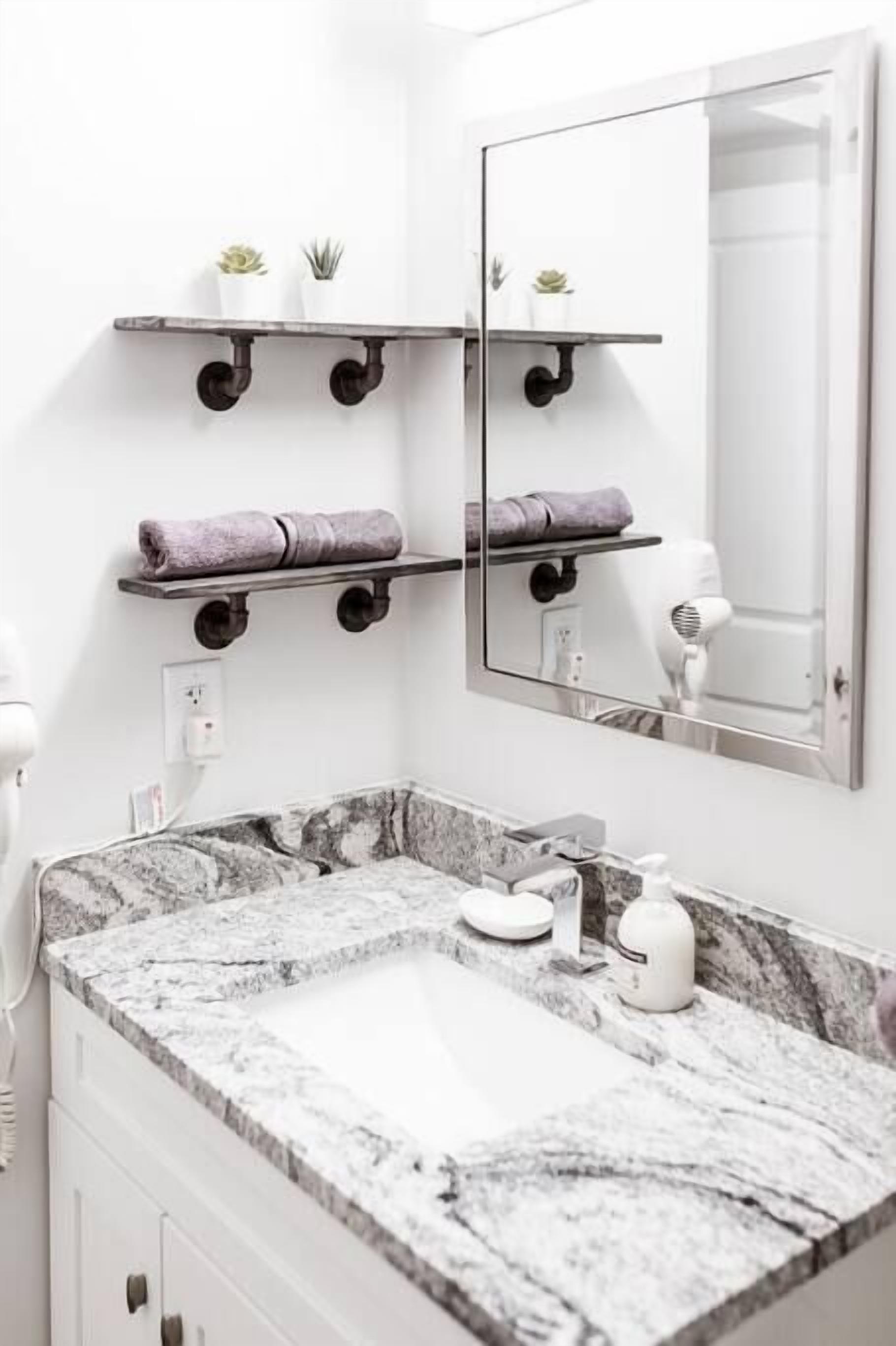 A bathroom with a marble sink, towel racks, and a mirror.