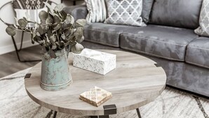 Ein runder Couchtisch aus Holz mit einer Vase mit Grünpflanzen und einer Papiertuchbox.