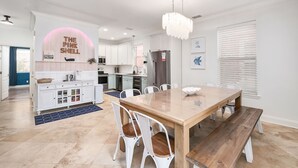 Een moderne keuken met witte kasten, een centraal eiland en een eetgedeelte met een houten tafel en stoelen.