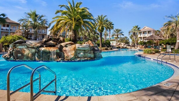 Zwembad van een resort met een rotsdecoratie en palmbomen.