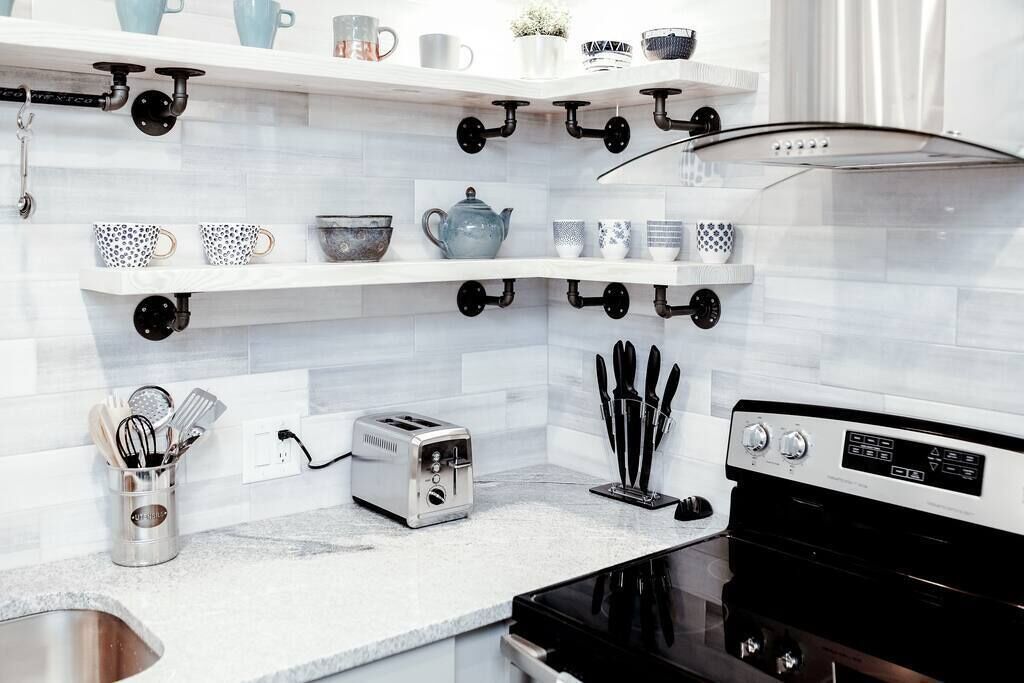 Una cocina moderna con armarios blancos, una estufa negra y diversos utensilios y electrodomésticos.