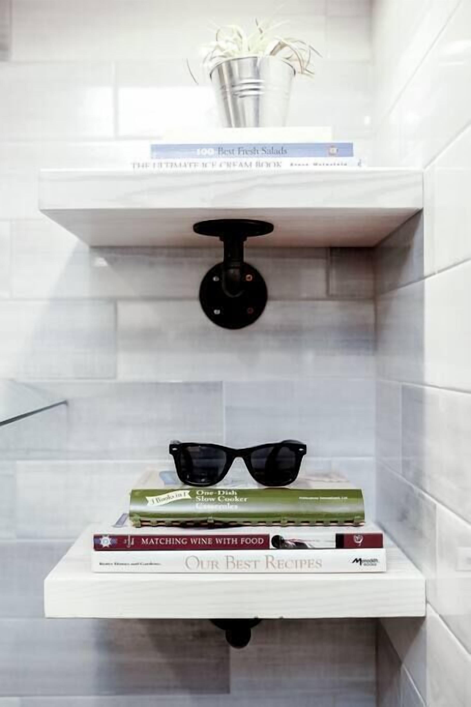 A bathroom with a white shelf holding books and a potted plant.