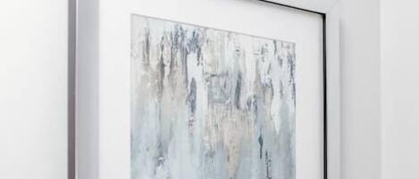 A framed abstract painting on a white wall.