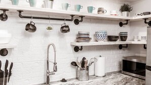 A kitchen with white brick walls, a stainless steel sink, and various kitchen utensils on the counter. - Renovated 2story (9C) OSU/Central ❤Near EVERYTHING (Columbus)
