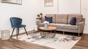 A living room with a grey sofa, a blue chair, a round coffee table, and a patterned rug. - Renovated 2story (9C) OSU/Central ❤Near EVERYTHING (Columbus)