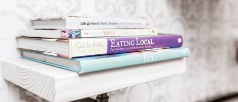 Una pila de libros de cocina sobre un estante blanco.