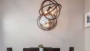 A dining area with a modern chandelier, black chairs, and a wooden table.