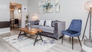 A modern living room with a grey sofa, a blue armchair, a wooden coffee table, and a floor lamp.