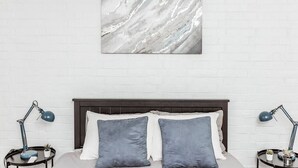A bedroom with a white brick wall, a marble artwork, a dark wooden headboard, two grey pillows, and two bedside tables with lamps. - Newly Renovated (E) OSU/Central ❤Near EVERYTHING (Columbus)