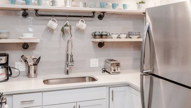 A modern kitchen with white cabinets, a stainless steel refrigerator, a sink, and various kitchen utensils. - Newly Renovated (E) OSU/Central ❤Near EVERYTHING (Columbus)