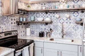 A kitchen with patterned tiles, a stove, a sink, and shelves with kitchenware. - Newly Renovated(A) OSU/Central ❤Near EVERYTHING! (Columbus)
