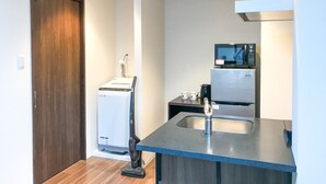 A compact kitchen with a microwave, refrigerator, and a vacuum cleaner. - Hotel LiveMax Nagoya-Shinkansenguchi (Nagoya)