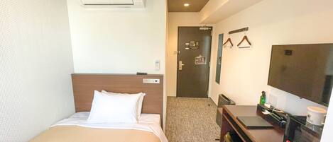 Une chambre d’hôtel équipée d’un lit, d’un bureau, d’une télévision et d’un appareil de climatisation.