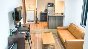 A compact living space with a sofa, a coffee table, a TV, a desk, and a kitchenette area. - Hotel LiveMax Nagoya-Shinkansenguchi (Nagoya)