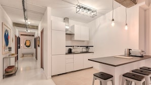 Eine moderne Küche mit weißen Schränken, einer zentralen Kochinsel mit Sitzgelegenheiten, einer Kaffeemaschine und einem Toaster.