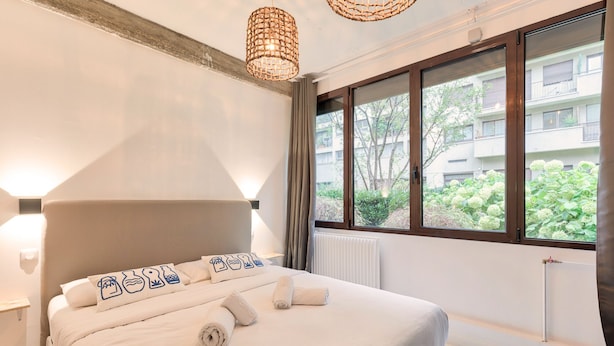 Ein modernes Schlafzimmer mit einem großen Bett, einer Heizung und Blick auf Grün.