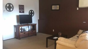 A living room with a beige sofa, a wooden entertainment unit with a TV, and a small coffee table. - HCHideaway-Quiet, Cottagelike!  Pet Friendly!  Queen bed! (Aberdeen)