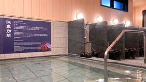 Des toilettes publiques avec un sol carrelé, un panneau mural avec du texte et un sèche-mains.