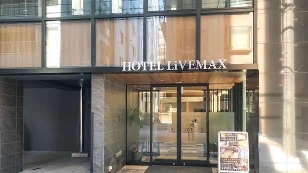 L’entrée de l’HÔTEL LIVEMAX se distingue par une porte en verre et un sol à carreaux.