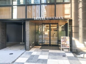 L’entrée de l’HÔTEL LIVEMAX se distingue par une porte en verre et un sol à carreaux.