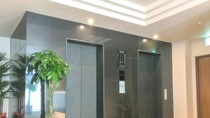 Un ascenseur moderne doté d’un écran numérique, d’une plante en pot et d’un sol carrelé.