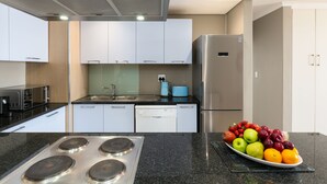 Eine moderne Küche mit weißen Schränken, einem Edelstahl-Kühlschrank, einem Geschirrspüler und einer Arbeitsplatte aus Granit.