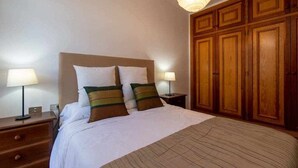 A hotel room with a bed, nightstands, lamps, and wooden wardrobe.