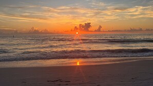 A beach with waves, a sunset, and a distant shoreline. - Rare last-minute DISCOUNT in Indian Rocks Beach! Renovated 3BR WATERFRONT single family home with private dock sleeps 8, WALK to the sugar-white sand beach, Includes paddle board, beach chairs, wagon & umbrellas.  3bdrm, 2 bthrm, sleeps up to 8. (Indian Rocks Beach)