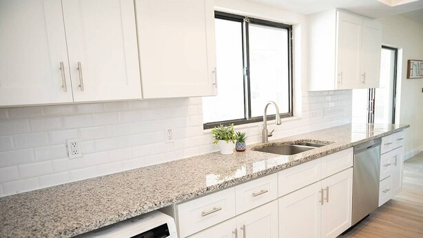 A modern kitchen with white cabinets, a granite countertop, a built-in dishwasher, and a window above the sink. - Rare last-minute DISCOUNT in Indian Rocks Beach! Renovated 3BR WATERFRONT single family home with private dock sleeps 8, WALK to the sugar-white sand beach, Includes paddle board, beach chairs, wagon & umbrellas.  3bdrm, 2 bthrm, sleeps up to 8. (Indian Rocks Beach)