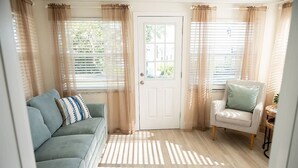 A room with a light blue sofa, a white chair, and a door. - Rare last-minute DISCOUNT in Indian Rocks Beach! Renovated 3BR WATERFRONT single family home with private dock sleeps 8, WALK to the sugar-white sand beach, Includes paddle board, beach chairs, wagon & umbrellas.  3bdrm, 2 bthrm, sleeps up to 8. (Indian Rocks Beach)