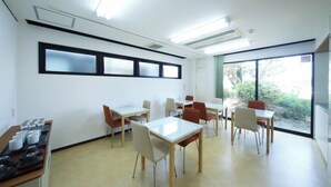 A conference room with tables and chairs, a whiteboard, and a window with a view of greenery. - Isesaki Station Hotel (Isesaki)