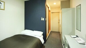 A hotel room with a bed, a desk with a telephone, and a mirror. - Isesaki Station Hotel (Isesaki)
