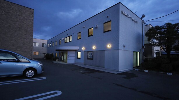A modern building with a flat roof, a garage door, and a small parking area. - Isesaki Station Hotel (Isesaki)