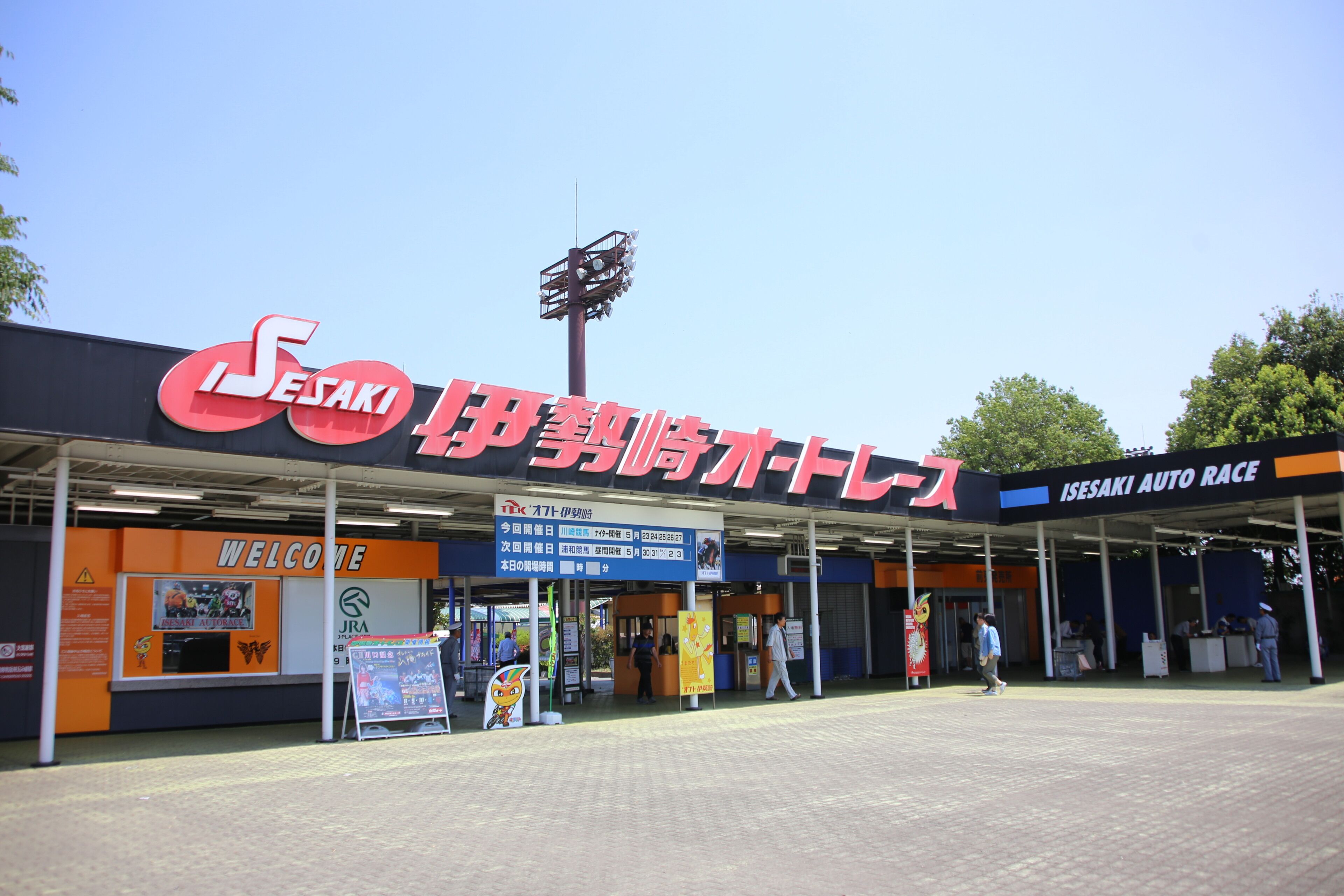 An auto race event entrance with signage, a welcome board, and a covered area.