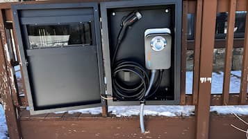 Un cuadro eléctrico exterior con un puerto de carga y un cable.