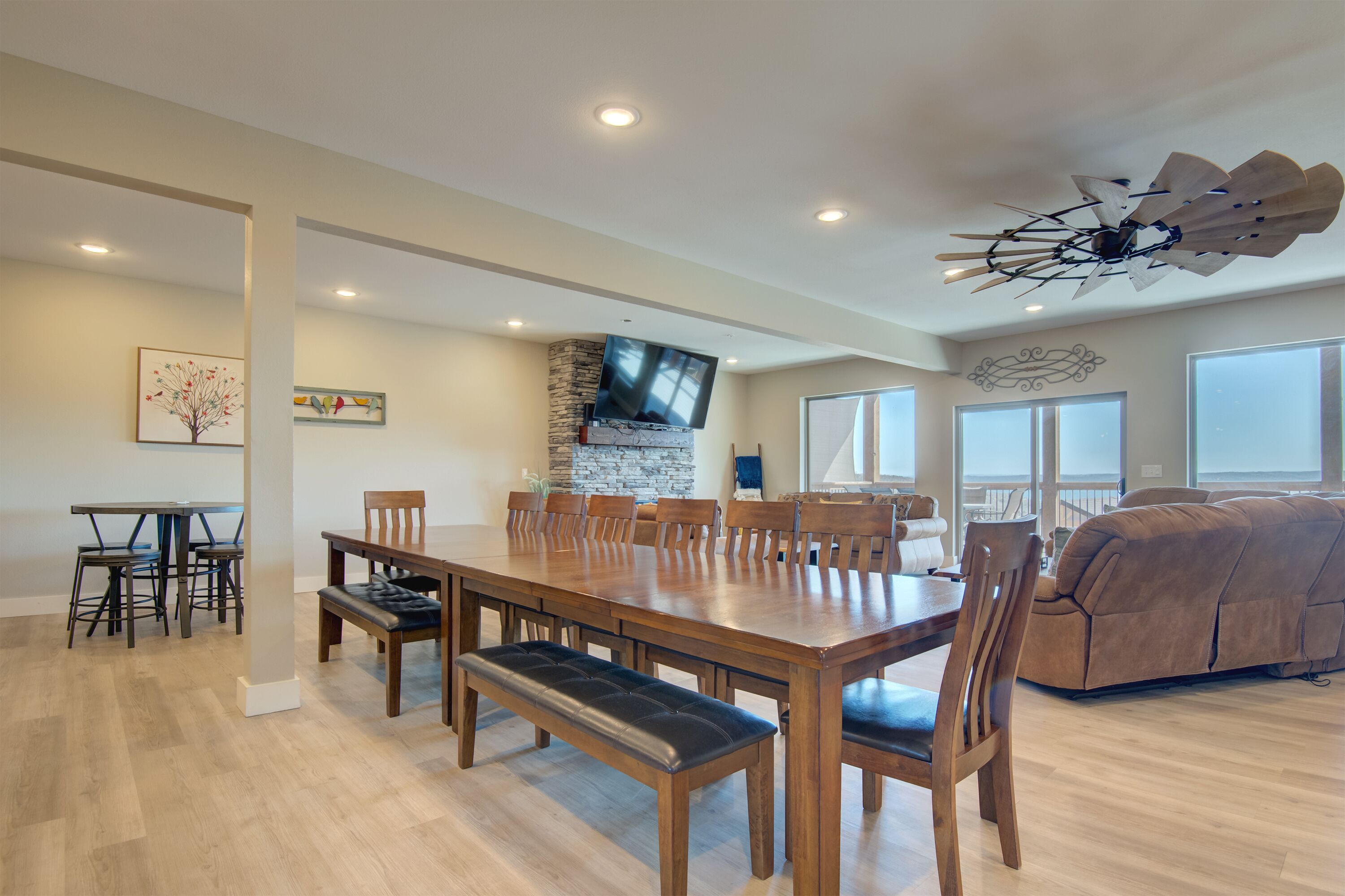 A spacious dining area with a long wooden table and multiple chairs, a comfortable bench, and a stone accent wall.
