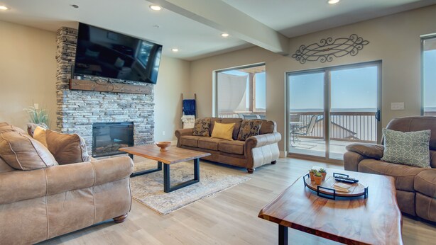 A spacious living room with a stone fireplace, leather sofas, and a large TV mounted on the wall. - Stay awhile and prolong your smile (Branson)