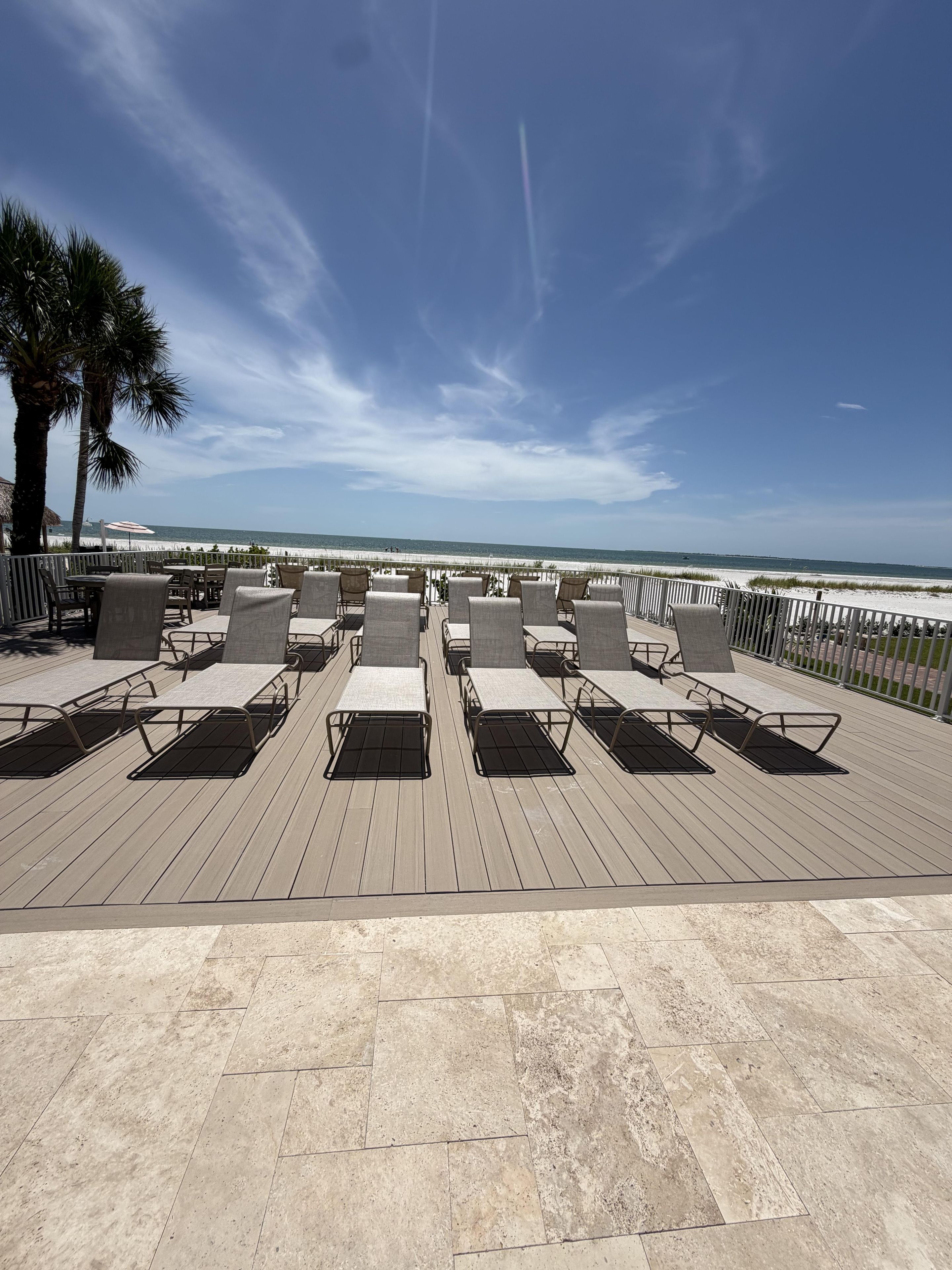 Eine Terrasse mit Liegestühlen mit Blick auf einen Strand.
