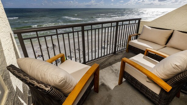 Ein Balkon mit Korbmöbeln und Blick auf das Meer.